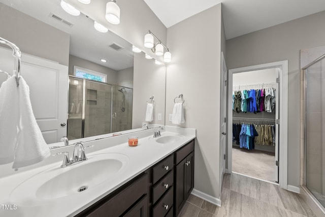 bathroom featuring a stall shower, double vanity, and a spacious closet