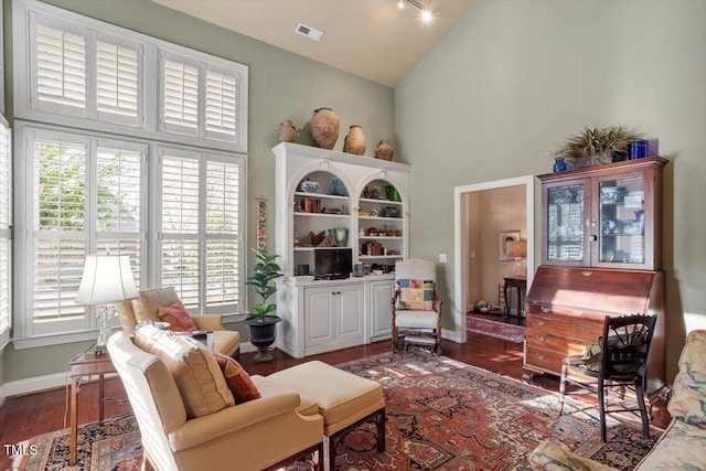 living area with high vaulted ceiling, healthy amount of natural light, wood finished floors, and baseboards