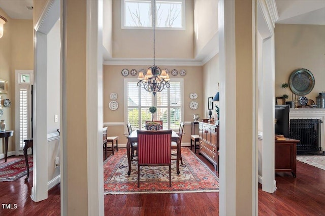 dining space with a chandelier, dark wood-style floors, crown molding, a towering ceiling, and baseboards