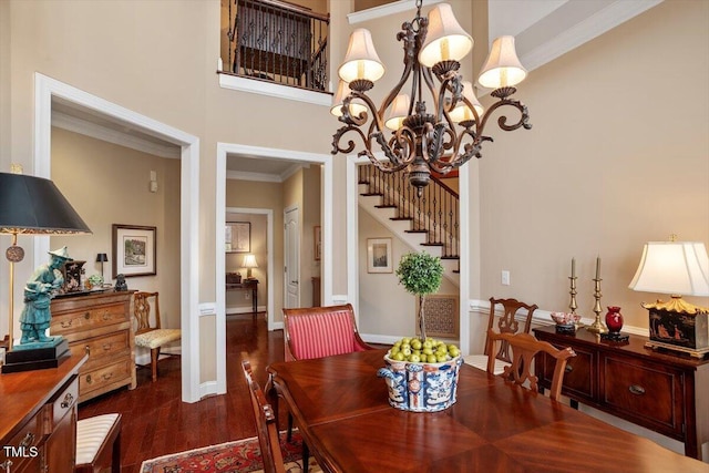 dining room with dark wood finished floors, stairs, ornamental molding, a chandelier, and a towering ceiling