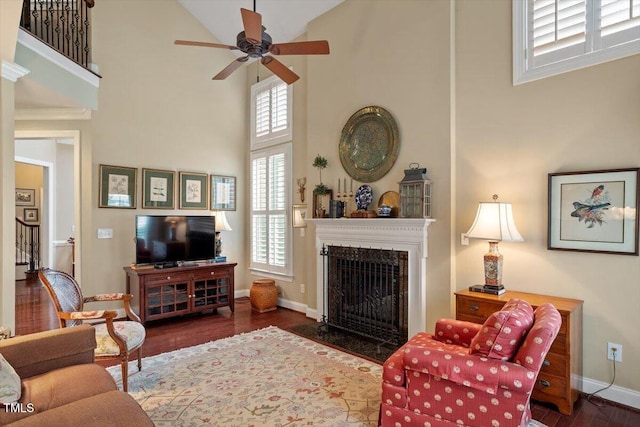 living room with high vaulted ceiling, a ceiling fan, a high end fireplace, wood finished floors, and baseboards