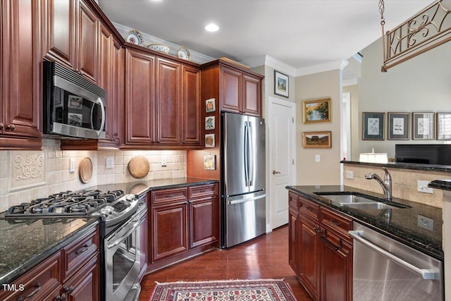 kitchen with stainless steel appliances, a sink, dark stone countertops, decorative backsplash, and ornamental molding