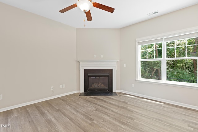 unfurnished living room featuring wood finished floors, ceiling fan, a fireplace with flush hearth, and baseboards