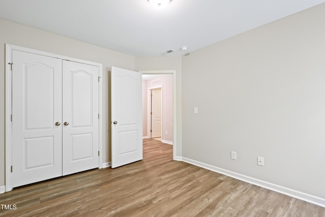 unfurnished bedroom featuring wood finished floors, a closet, and baseboards
