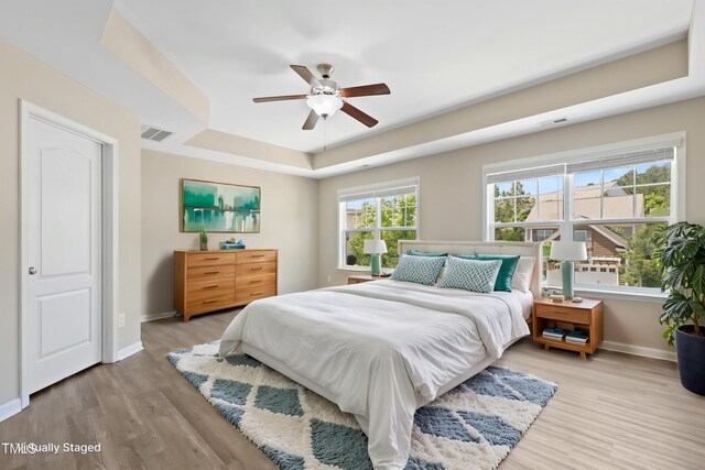 2513 Magnolia Tree Ln, Durham, NC 27703 - bedroom featuring a tray ceiling, baseboards, wood finished floors, and a ceiling fan