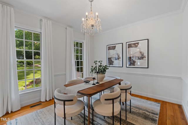 dining room featuring a chandelier, plenty of natural light, light wood-style flooring, and ornamental molding