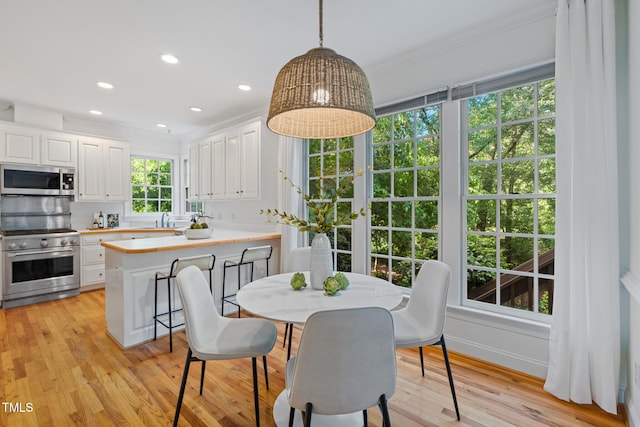 dining room with ornamental molding, light wood-style floors, and recessed lighting