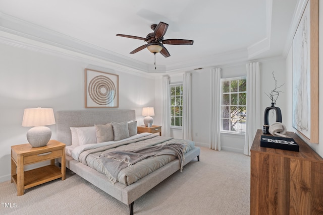 bedroom featuring a raised ceiling, ornamental molding, light colored carpet, baseboards, and ceiling fan