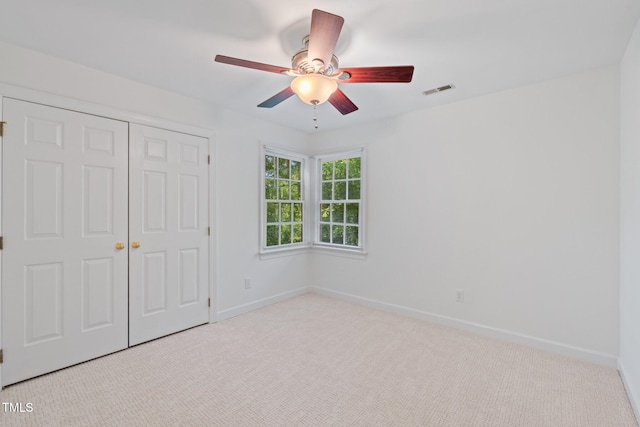 unfurnished bedroom featuring carpet floors, a closet, baseboards, and ceiling fan