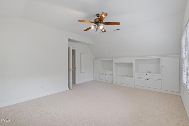 unfurnished bedroom with lofted ceiling, light colored carpet, a ceiling fan, and baseboards