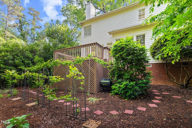 back of house featuring a chimney and a wooden deck