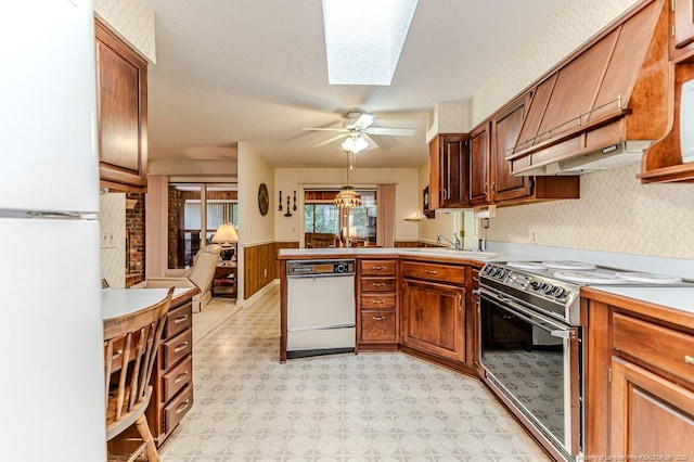 241 Firetree Ln, West End, NC 27376 - kitchen with a peninsula, light floors, wainscoting, white appliances, and custom range hood