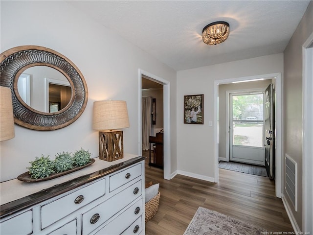 hallway featuring visible vents, baseboards, and dark wood-style floors