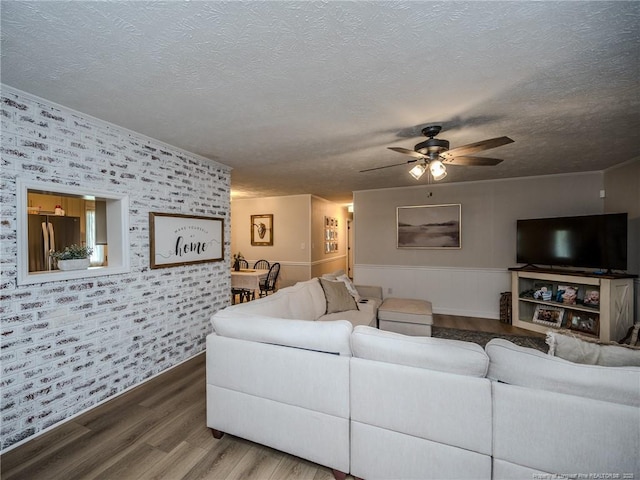living area featuring ceiling fan, a textured ceiling, wallpapered walls, and wood finished floors