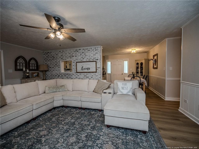 living area with ornamental molding, a textured ceiling, a ceiling fan, and wood finished floors