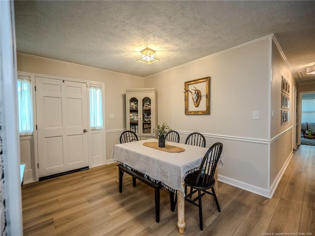 dining room featuring ornamental molding, a textured ceiling, and wood finished floors