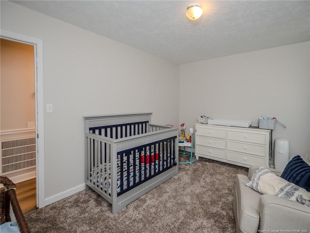 bedroom with baseboards, carpet flooring, a crib, and a textured ceiling