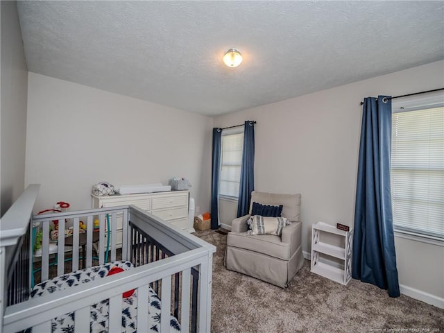 bedroom featuring a textured ceiling, carpet floors, baseboards, and a crib