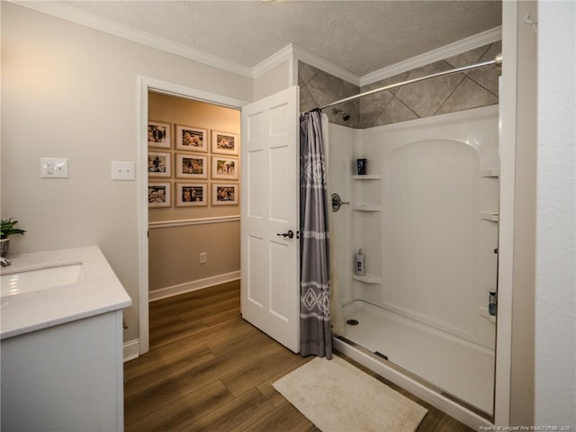 full bathroom featuring a textured ceiling, a shower with shower curtain, vanity, crown molding, and wood finished floors