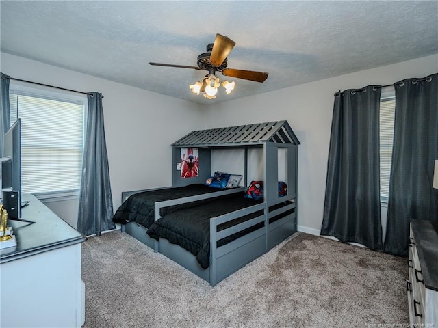 carpeted bedroom with baseboards, ceiling fan, and a textured ceiling