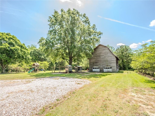 view of yard with a playground, a garage, an outbuilding, and a barn