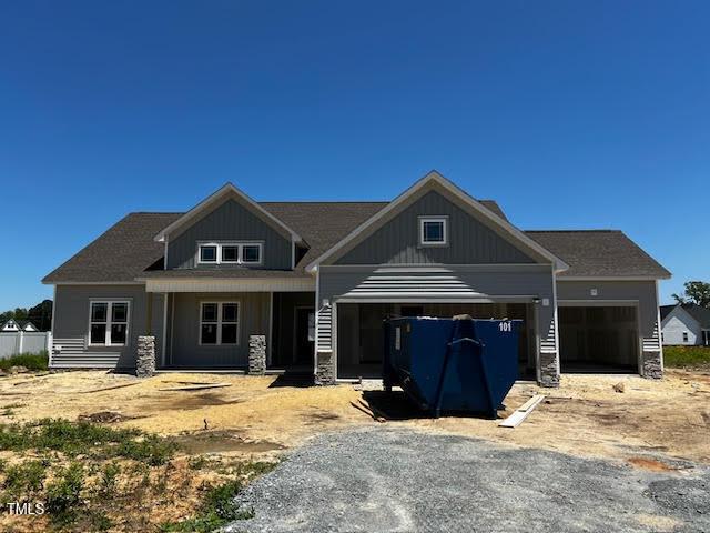 craftsman house featuring a garage, board and batten siding, driveway, and stone siding