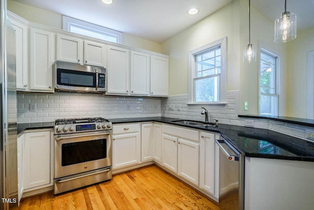kitchen featuring appliances with stainless steel finishes, a sink, white cabinetry, light wood-type flooring, and recessed lighting