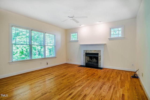unfurnished living room with plenty of natural light, light wood-type flooring, a fireplace, and baseboards