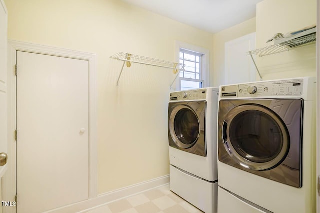 laundry area featuring washing machine and clothes dryer, light flooring, and baseboards