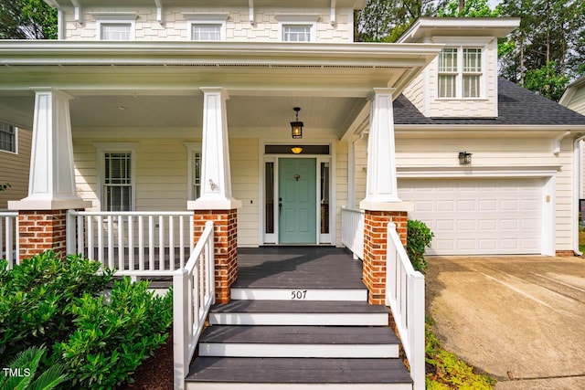doorway to property with covered porch, driveway, a shingled roof, and a garage