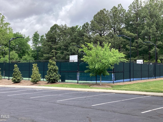 uncovered parking lot with fence and a tennis court