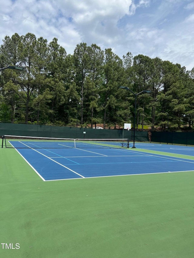 view of tennis court featuring community basketball court and fence