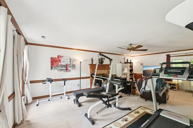 exercise room with a ceiling fan, carpet flooring, crown molding, and baseboards