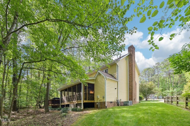 view of property exterior with a chimney, a yard, cooling unit, and a sunroom
