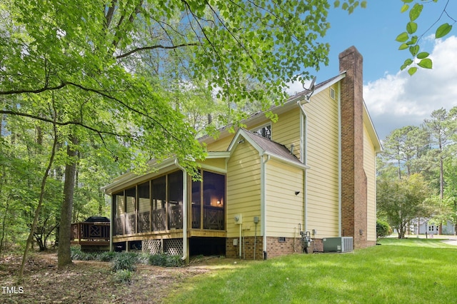 rear view of property with a sunroom, a chimney, a lawn, a deck, and central AC unit