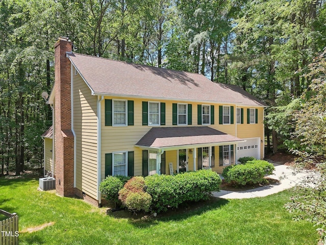 colonial house with an attached garage, central AC, a front lawn, a chimney, and a shingled roof