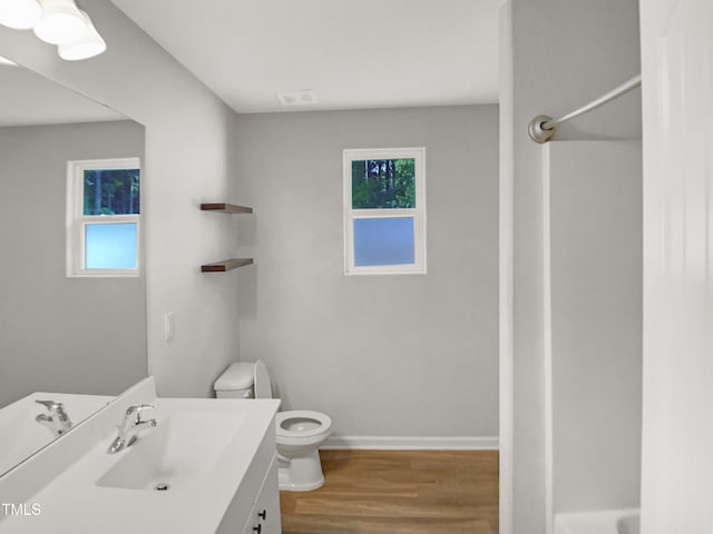 bathroom with toilet, baseboards, vanity, and wood finished floors