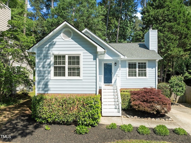 view of front of house featuring a chimney, a shingled roof, and fence
