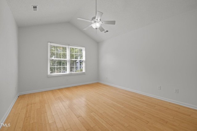 empty room with ceiling fan, light wood-style flooring, lofted ceiling, baseboards, and a textured ceiling