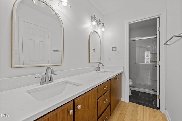 full bathroom featuring toilet, double vanity, wood finished floors, and a shower with shower door