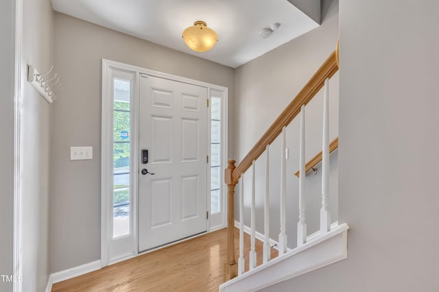 foyer entrance featuring light wood-style floors, stairs, and baseboards