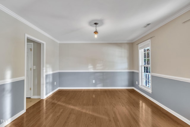spare room with wood finished floors, baseboards, and crown molding