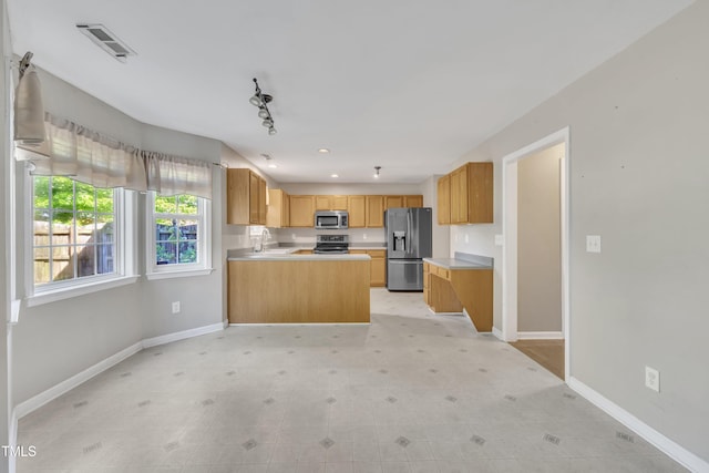 kitchen featuring appliances with stainless steel finishes, a sink, baseboards, light countertops, and a peninsula