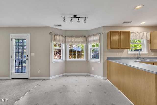 kitchen featuring baseboards, a sink, light countertops, recessed lighting, and track lighting