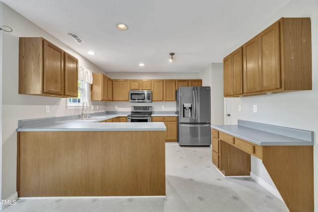 kitchen with appliances with stainless steel finishes, a sink, light countertops, a peninsula, and baseboards