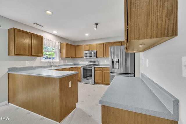 kitchen featuring stainless steel appliances, a sink, a peninsula, recessed lighting, and light countertops
