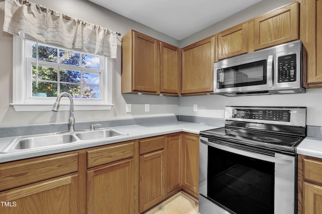 kitchen featuring appliances with stainless steel finishes, a sink, light countertops, and light tile patterned floors