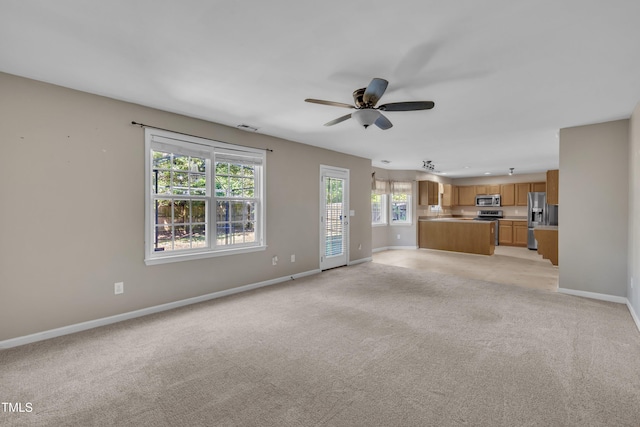 unfurnished living room with a ceiling fan, baseboards, and light carpet