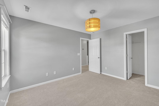 unfurnished bedroom with carpet floors, baseboards, a walk in closet, and a closet