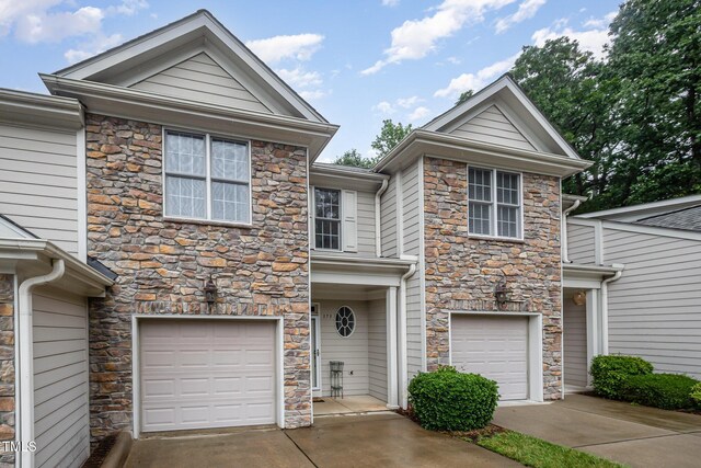 view of front of property with stone siding, an attached garage, and concrete driveway